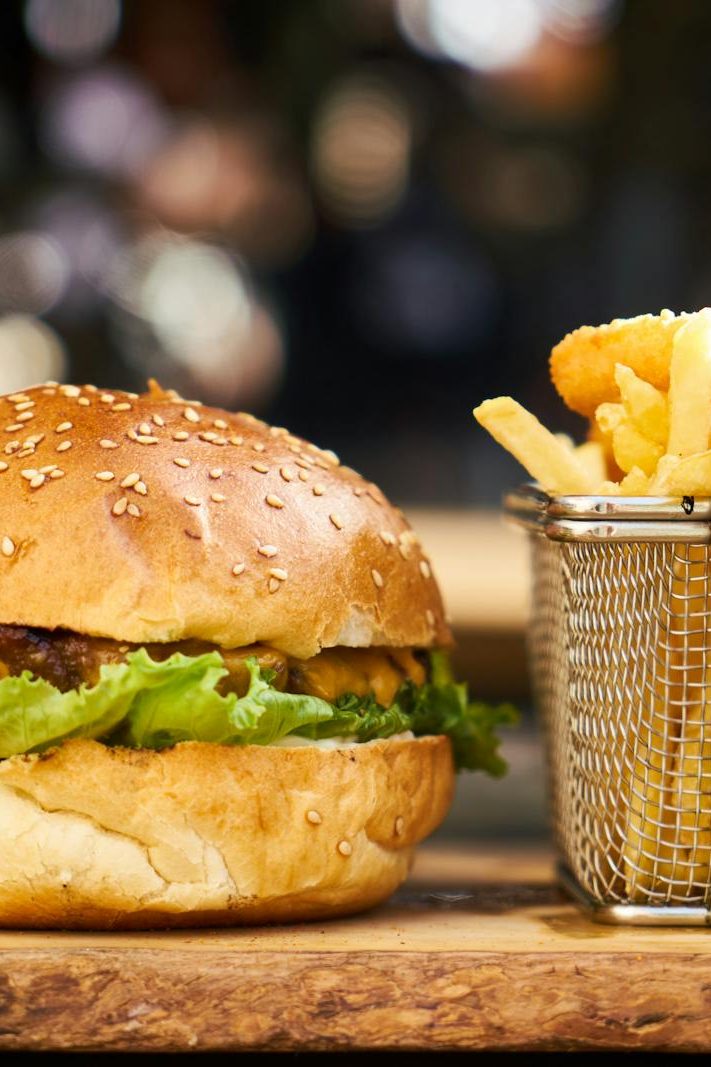 A delicious cheeseburger with crispy french fries served on a wooden platter, perfect for lunch or dinner.