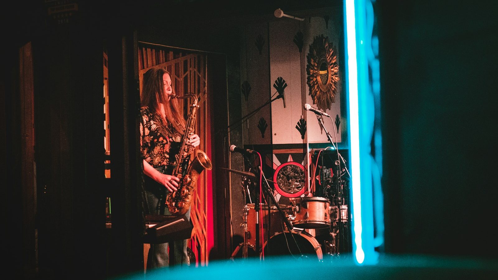 woman playing saxophone on stage near wall clock